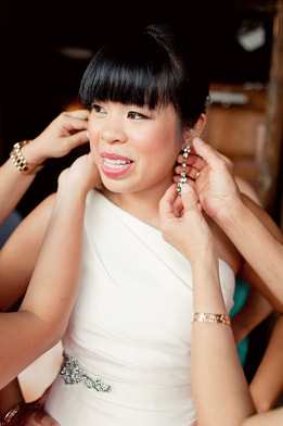 Bridal party helping to put earrings on Asian bride with bangs